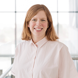 A woman with blond hair and wearing a white shirt smiles at the camera.